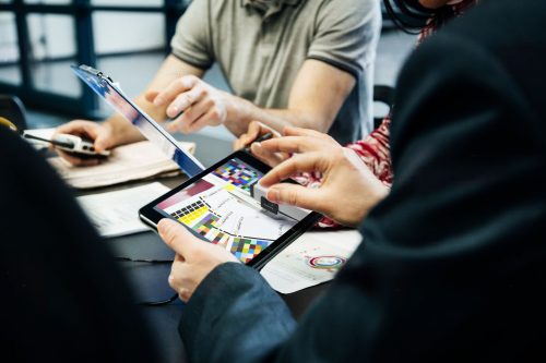 A close up of a printing factory management team holding a meeting and looking at data on digital tablets.